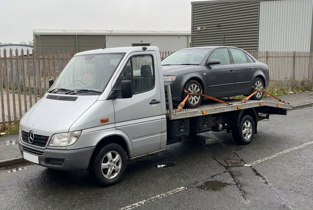 A car strapped down and secured flat on the recovery truck bed on an industrial estate